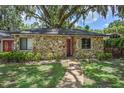 Stone house exterior with red door, landscaping, and large oak tree at 3355 Scarlet Dr, Sanford, FL 32773