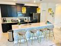 Modern kitchen with island, quartz countertops, and dark cabinets at 962 Splash Shot Pl, Davenport, FL 33896