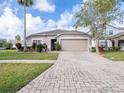 Tan house with a two-car garage and a brick paver driveway at 4725 Cumbrian Lakes Dr, Kissimmee, FL 34746