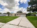 House exterior featuring a beige color, a two-car garage, and a well-maintained lawn at 3235 Cross Fox Dr, Mulberry, FL 33860
