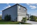 Two-story house with gray siding, white garage door, and landscaping at 305 Jovana Rd, Davenport, FL 33837