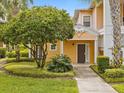 Front entrance of a two-story yellow home with landscaping and walkway at 401 New Providence Promenade # 12401, Davenport, FL 33897