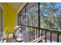 A screened balcony with two chairs and a small table overlooking lush trees at 315 Lucaya Loop # 315, Davenport, FL 33897