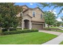 Tan two-story house with a landscaped yard and a brick driveway at 1424 Rolling Fairway Dr, Davenport, FL 33896