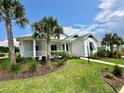White house with blue accents, front porch, palm trees, and manicured lawn at 1077 Sugar Loaf Key Loop, Lady Lake, FL 32159