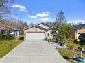 Tan house with white garage door, landscaped garden, and paved driveway at 132 Meadow Blvd, Sanford, FL 32771