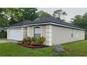 Side view of a beige house with a dark grey roof, landscaping, and a large rock at 1312 Swiss Ln, Deltona, FL 32738