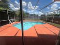 Relaxing kidney-shaped pool with a screened enclosure and orange colored deck at 2603 Coventry Ln, Ocoee, FL 34761