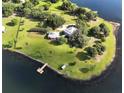 Aerial view of a waterfront property with a large house, expansive lawn, and private dock at 16600 Cleveland Ln, Umatilla, FL 32784