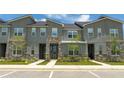 Three-unit townhome building, gray siding, stone accents, and landscaping at 1692 Tropical Palms Cir, Kissimmee, FL 34747