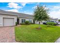 Exterior view of a light beige villa with a brick pathway and lush green lawn at 2877 Attwater Loop, Winter Haven, FL 33884