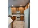 Well-lit kitchen features light wood cabinets, white appliances, and tile floor at 10420 Kiplinger Ln # 238, Orlando, FL 32829