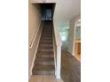 View of carpeted staircase leading to upper level, with glimpses of living area and kitchen at 10420 Kiplinger Ln # 238, Orlando, FL 32829