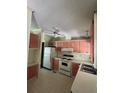 Retro kitchen with pink cabinets and white appliances at 1705 Kiley Ct, The Villages, FL 32159