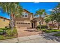Two-story house with beige exterior, brick driveway, and landscaping at 8810 Macapa Dr, Kissimmee, FL 34747