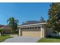 Tan one-story house with gray roof, two-car garage, and landscaped yard at 2635 Quarterdeck Ct, Kissimmee, FL 34743