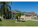 Tan one-story house with gray roof, two-car garage, and landscaped yard at 2635 Quarterdeck Ct, Kissimmee, FL 34743