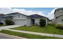 House exterior with gray siding, two-car garage, and solar panels at 462 Hamlet Loop, Davenport, FL 33837