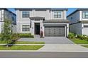 Two-story home with gray exterior, black garage door, and landscaping at 5936 High Seas Dr, Orlando, FL 32821
