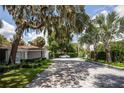 Long driveway leading to a white house with lush landscaping at 11130 Park Ave, Windermere, FL 34786