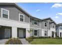Gray townhomes with teal shutters, landscaping and walkway at 936 Paradise Dr, Davenport, FL 33897