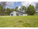 Gray house with a blue garage door and a grassy yard, nestled among trees at 5277 Sw 165Th Street Rd, Ocala, FL 34473