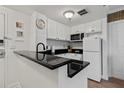 White kitchen with black countertops and modern appliances at 6165 Carrier Dr # 1206, Orlando, FL 32819