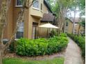 Ground floor patio with seating area and umbrella, surrounded by lush landscaping at 6320 Raleigh St # 604, Orlando, FL 32835