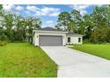 New construction home showcasing a gray garage door and a large yard at 556 Marion Oaks Pass, Ocala, FL 34473