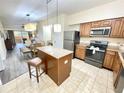 Open kitchen with island, stainless steel appliances, and view to living area at 12544 Floridays Resort Dr # 203-B, Orlando, FL 32821