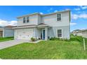 Two-story house with light gray siding, a two-car garage, and a well-maintained lawn at 1506 Finnigan Cir, Haines City, FL 33844