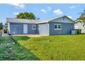 Back exterior view showing a large yard and access to the home at 7685 Ceres Dr, Orlando, FL 32822