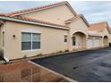 Tan stucco exterior of condo building with attached garage and brick walkway at 332 David Walker Dr # J-2, Tavares, FL 32778