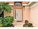 Home's entrance with white door and lush landscaping at 112 Paloma Dr, Davenport, FL 33837