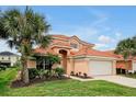 Two-story house with tile roof, two-car garage, and palm trees at 112 Paloma Dr, Davenport, FL 33837