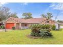 Single-story brick home with a red garage door and landscaped lawn at 897 Vicksburg St, Deltona, FL 32725