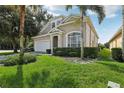 Two-story house with tan exterior, palm trees, and green lawn at 16838 Glenbrook Blvd, Clermont, FL 34714
