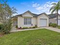 Single-story house with a beige exterior, white garage door, and a grassy yard at 2977 Kokomo Loop, Haines City, FL 33844