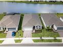 Three homes with garages and landscaping next to a lake at 2476 Pine Preserve Ct, St Cloud, FL 34771