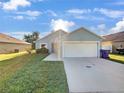 Cute one-story house with a white garage door and green grass at 1078 Osprey Cove Cir, Groveland, FL 34736