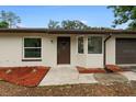 Front entrance of a renovated home featuring a brown door and landscaping at 21165 Sw Raintree St, Dunnellon, FL 34431