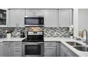 Modern kitchen with gray cabinets, stainless steel appliances, and quartz countertops at 13905 Fairway Island Dr # 1022, Orlando, FL 32837
