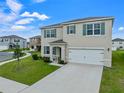 Two-story house with a two-car garage, landscaping, and a teal front door at 821 Sun Burst Rd, Winter Haven, FL 33880