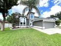 Gray two-story house with palm trees, well-maintained lawn, and a two-car garage at 14534 Potanow Trl, Orlando, FL 32837