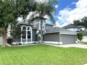 Two-story house with gray siding, landscaped lawn, and a two-car garage at 14534 Potanow Trl, Orlando, FL 32837