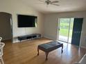 Bright living room with hardwood floors, large TV, and sliding glass doors leading to a patio at 4260 Climbing Aster Ct, Saint Cloud, FL 34772