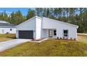 White house with gray garage door and landscaping at 7877 Sw 138Th Street Rd, Ocala, FL 34473