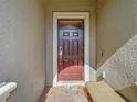 Dark brown front door with sidelights, welcome mat, and small bench at 1410 Wexford Way, Davenport, FL 33896