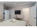 Bedroom with two white doors, a TV mounted above a dresser, and rolled-up towels on the bed at 1371 Tuscan Ter # 3204, Davenport, FL 33896