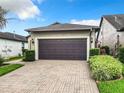 Two-car garage with paver driveway and lush landscaping at 515 Pamplona Pl, Davenport, FL 33837